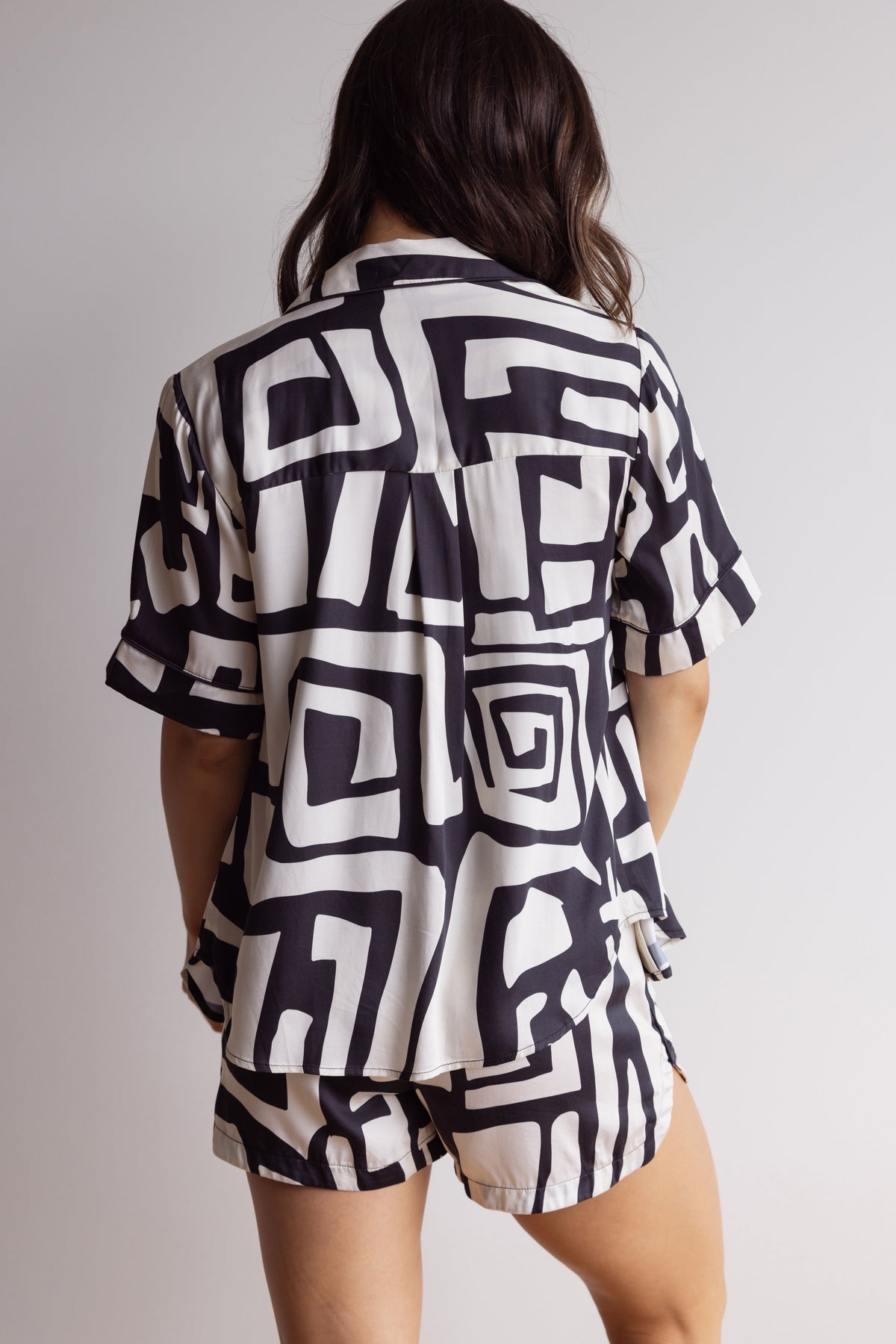 Woman wearing comfortable, breathable 100% bamboo PJ set, showing the back of a short sleeve pyjama top with a bold geometric print in black and cream.