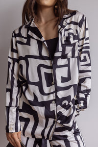 Woman wearing comfortable, breathable 100% bamboo PJ set showing a long sleeve pyjama top with button up design, pocket and bold geometric print in black and cream.