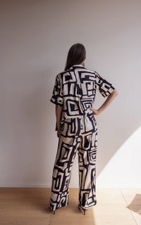 Back of a woman wearing bamboo pyjamas with a short sleeve shirt and pants. Bold geometric print in black and cream colours.