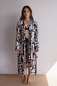 Woman wearing a lightweight, comfortable kimono-style robe. Made from silky-soft, breathable bamboo. Featuring a unique print design and a tie waist for an adjustable fit and hidden pockets. Perfect for relaxing.