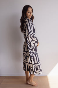 Woman wearing a kimono-style robe. Made from silky-soft, breathable bamboo with a flowing fit, featuring a unique print design in black and cream.  Beautiful design with a tie waist for an adjustable fit, pockets and wide sleeves. Perfect for lounging.