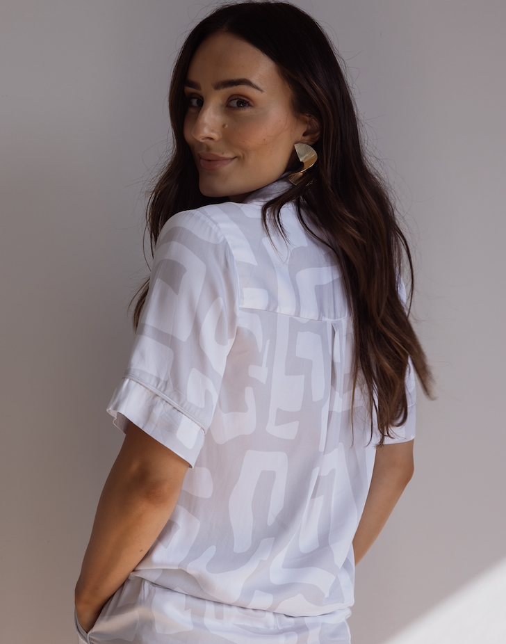 Woman wearing comfortable 100% bamboo PJs showing a short sleeve pyjama top with a bold geometric print in light grey and white.